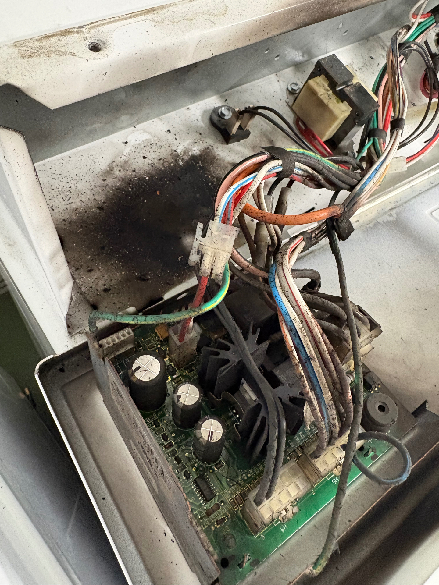 Washing machine control board and wiring harness covered in soot after an electrical blowout, documented during a Knapp's service call in the Portland area.